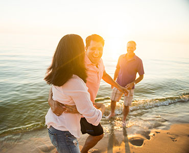 三位成年人在日落前海岸玩